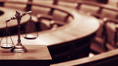 Leerer Gerichtssaal, im Vordergrund Waage der Justitia